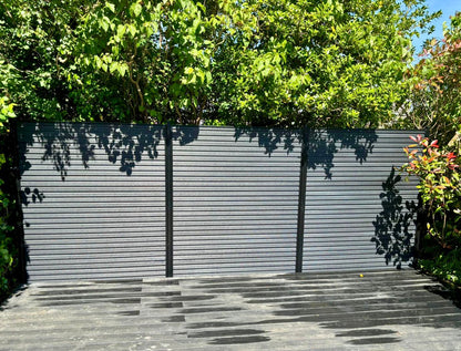 a composite decking area with anthracite fence boards pictured on a summers day.