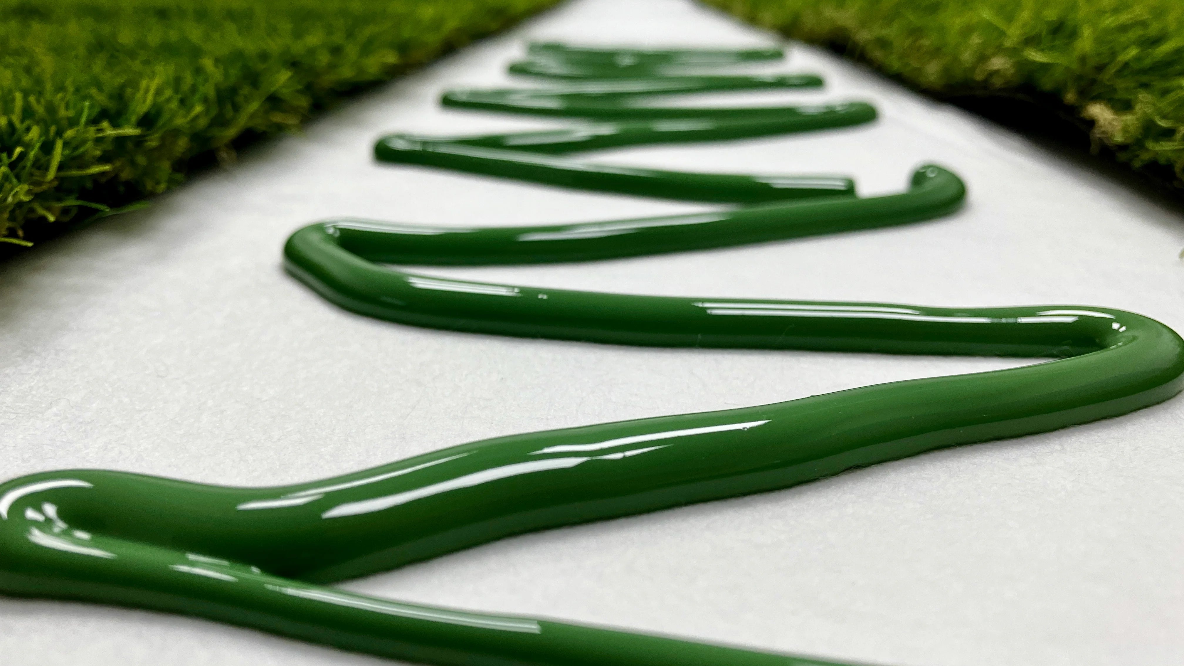 A close up picture of artificial grass ready to be joined together, green artificial grass adhesive has been spread out across seem tape.