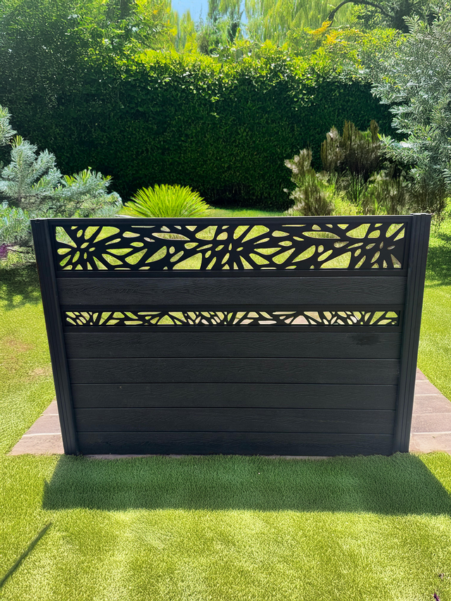 Black garden screen with decorative cut-out design on a grassy lawn