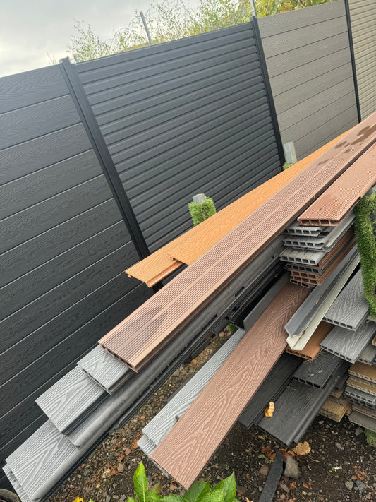 A stillage containing a range of B Grade  scratched or chipped composite decking boards in a range of brown and grey colours.