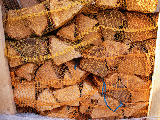 A small stack of silver Birch kiln dried firewood logs in orange nets.