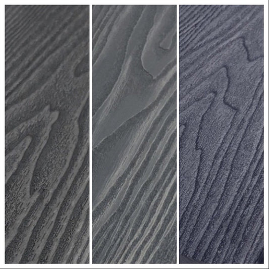 Three grey composite decking boards pictured close up showing the wood grain, charcoal and steel grey.