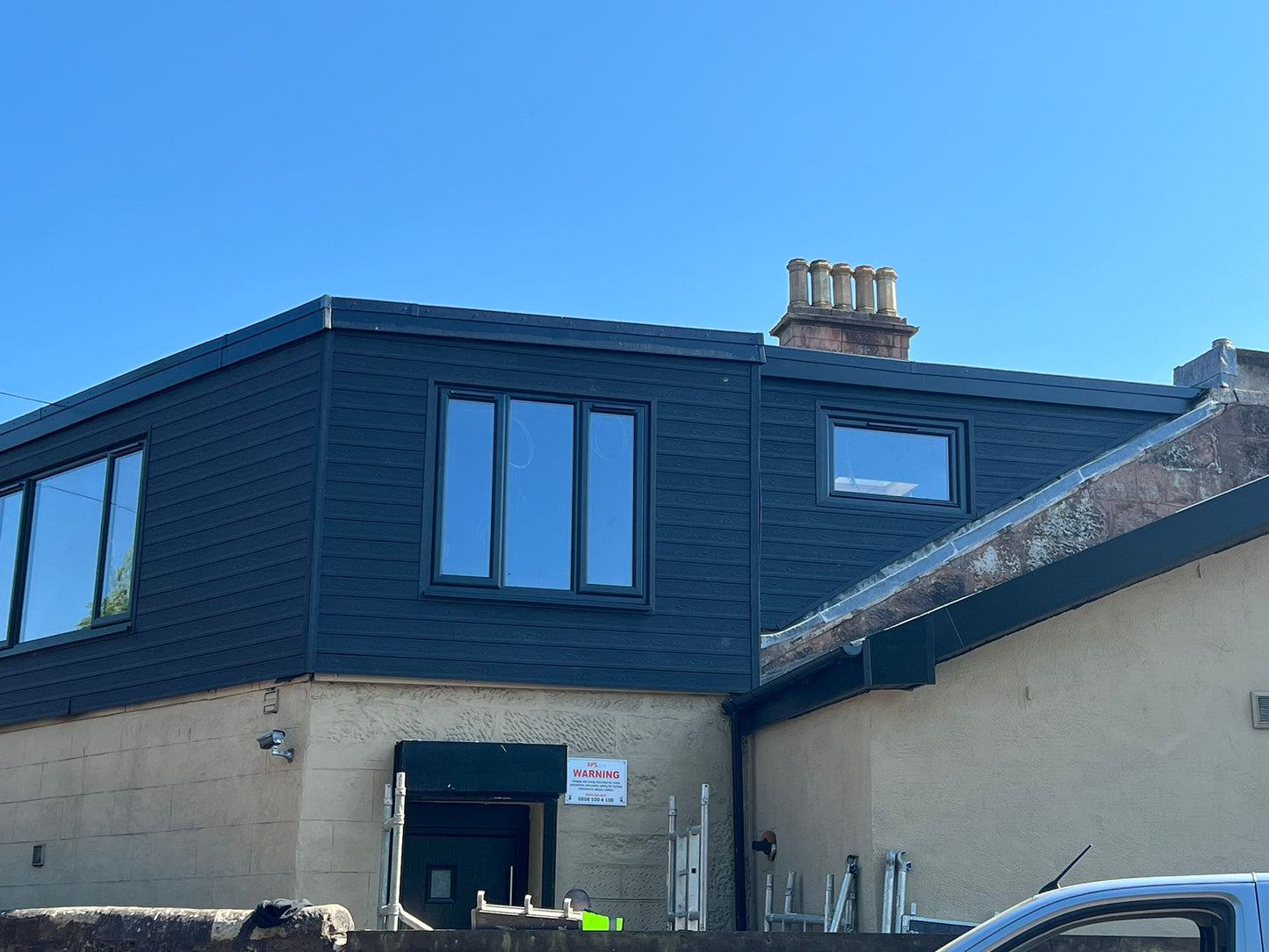 A large dormer clad in charcoal shiplap composite cladding with a wood grain pattern.