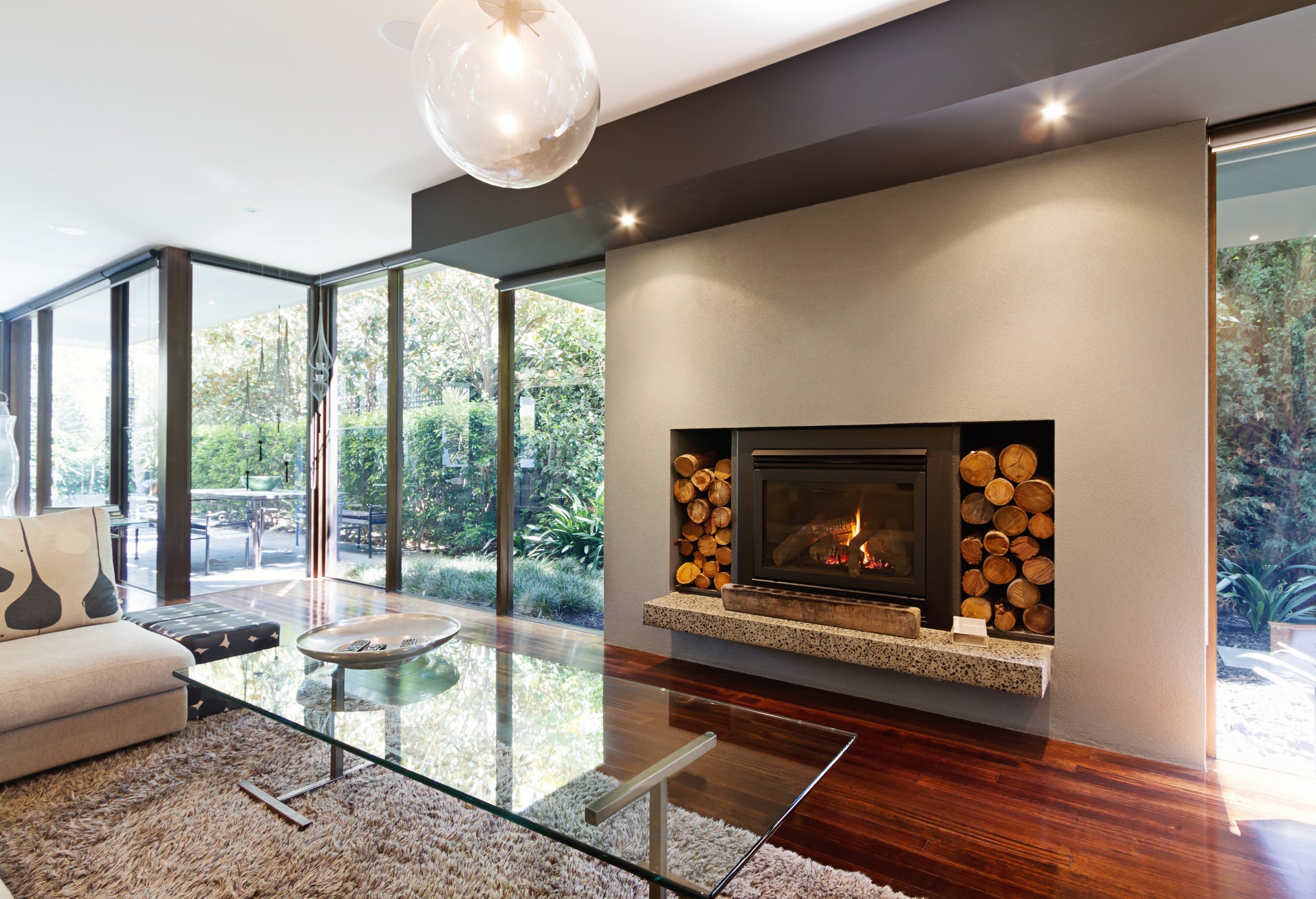 A modern wood burning stove with firewood logs stacked either side.