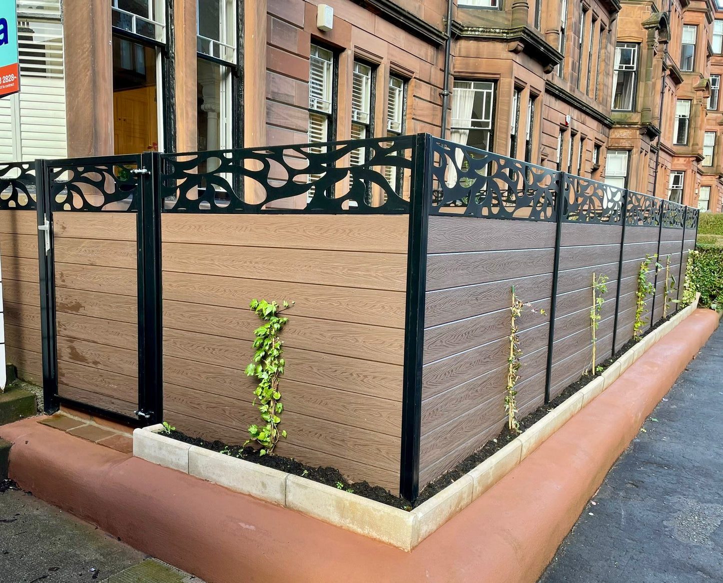 A 5ft high dark oak composite fence and gate, with a contemporary style fence topper in black.