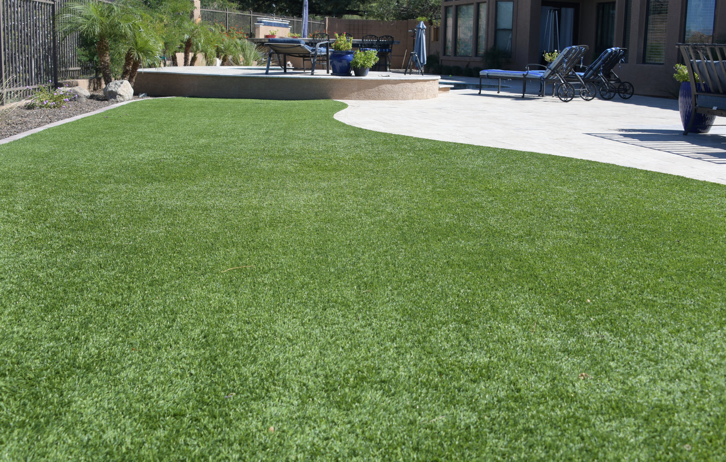 A back garden picture showing Durness 42mm artificial grass and patio seating area on a sunny afternoon.