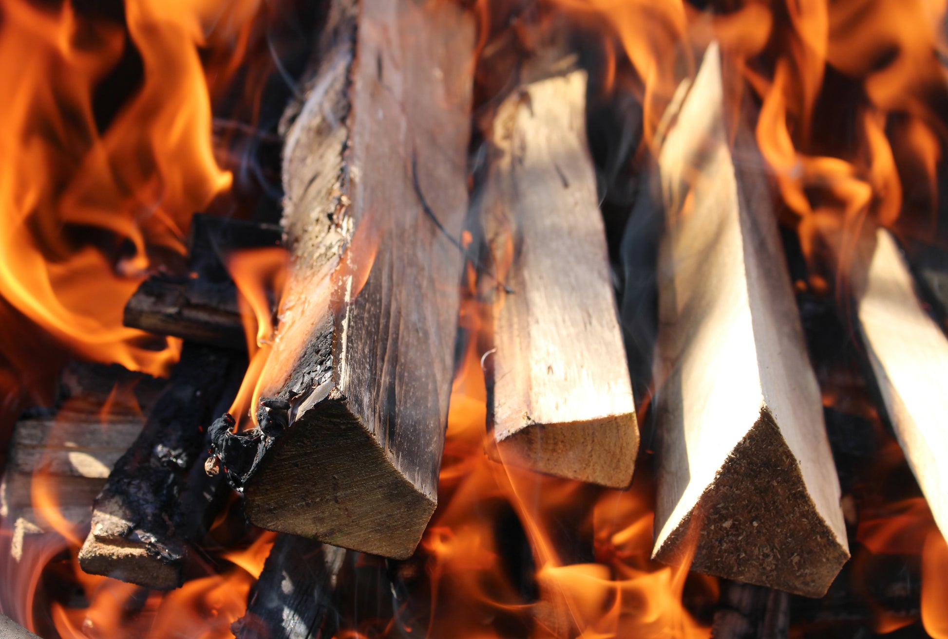 a small burning pile of kindling with large orange and gold flames and smoke.