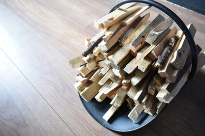 A neatly stacked pile of kindling on a black metal fire side stand.