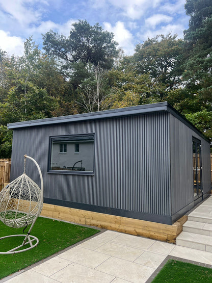 A picture of a garden room cladded in steel grey slatted cladding.