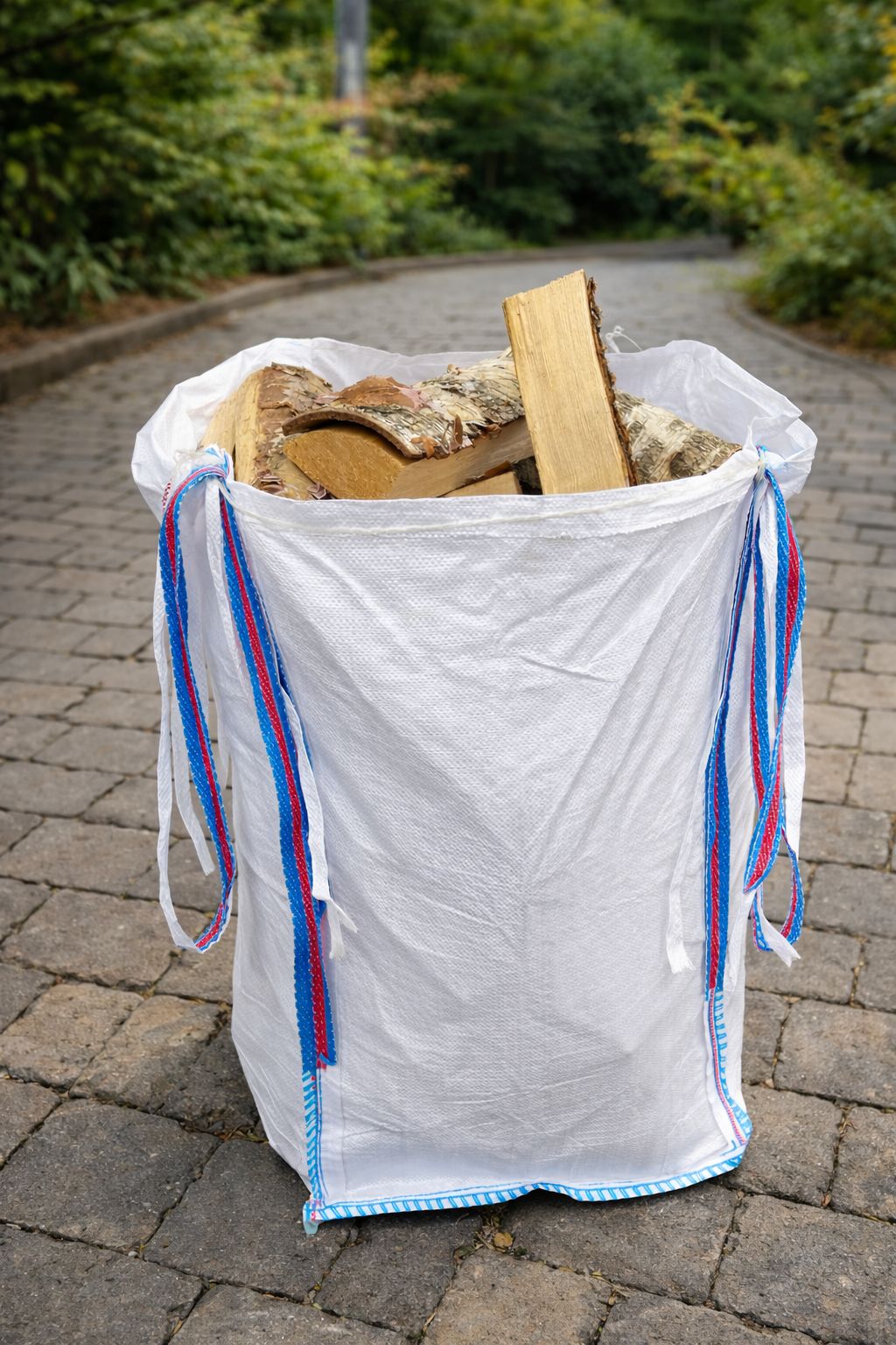 White bag with colorful straps filled with fire wood on a paved surface