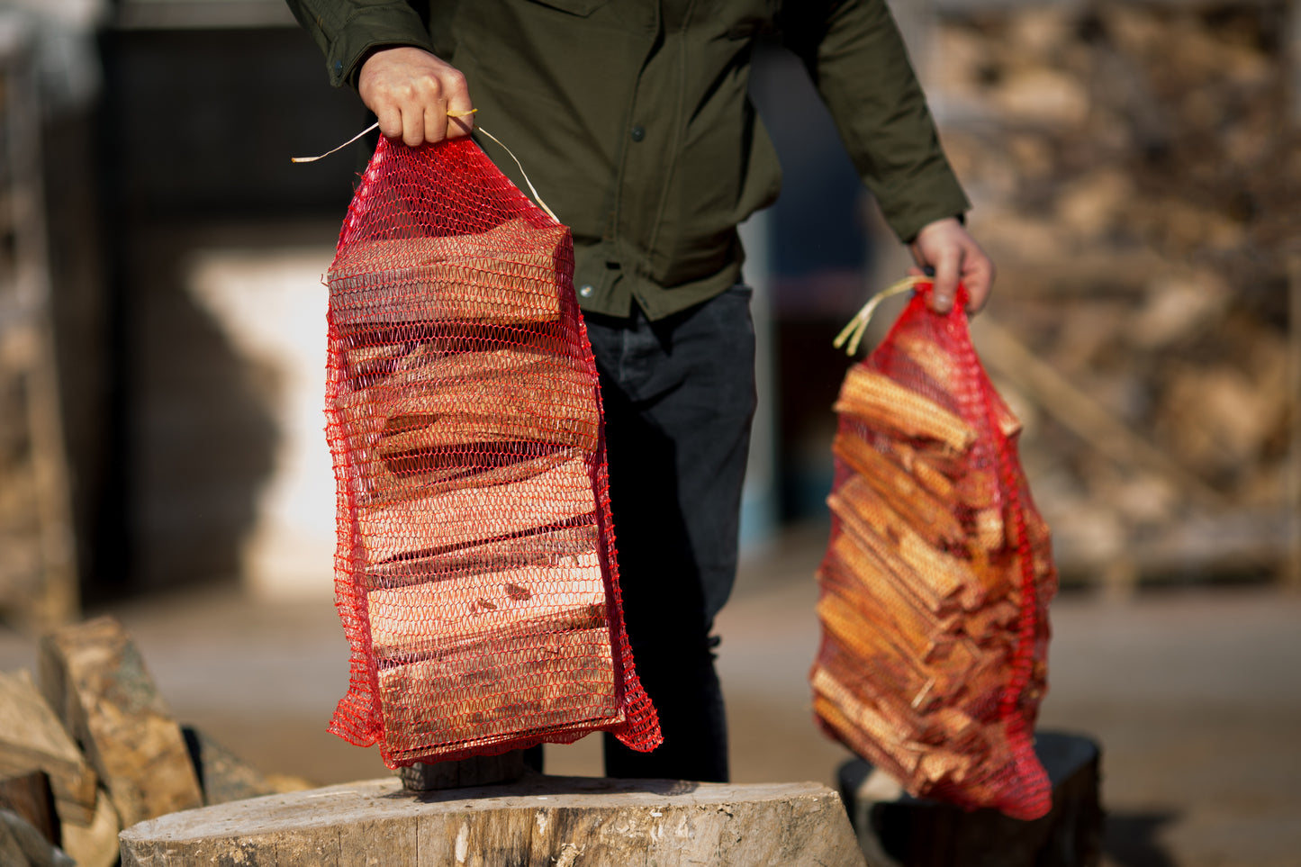 Man collecting two firewood log nets from The Grass Yard.