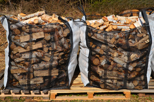 Two large builders bags of firewood logs stacked on pallets.