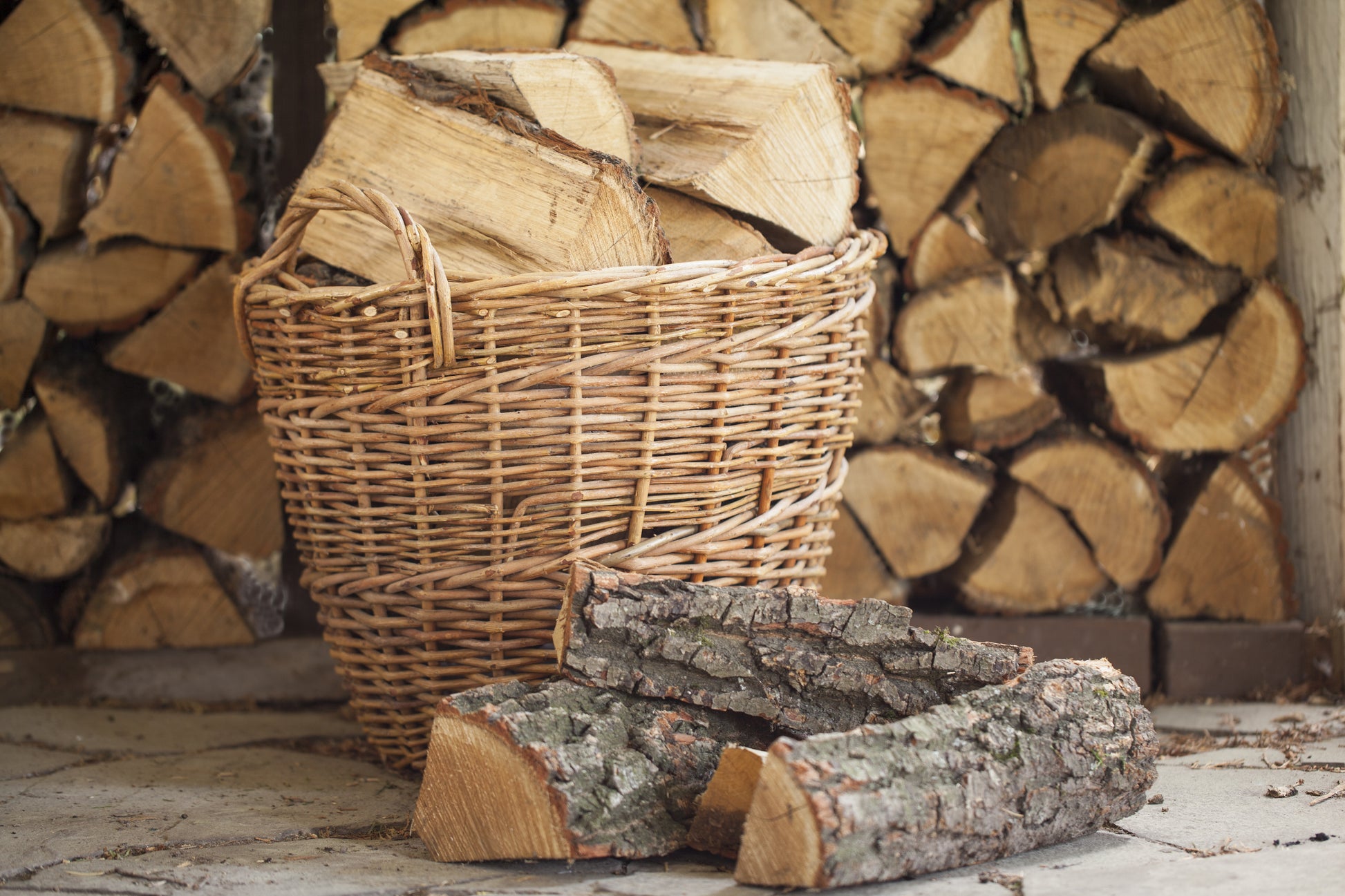 A traditional wicker basket full of oak logs sat in front of a log store.