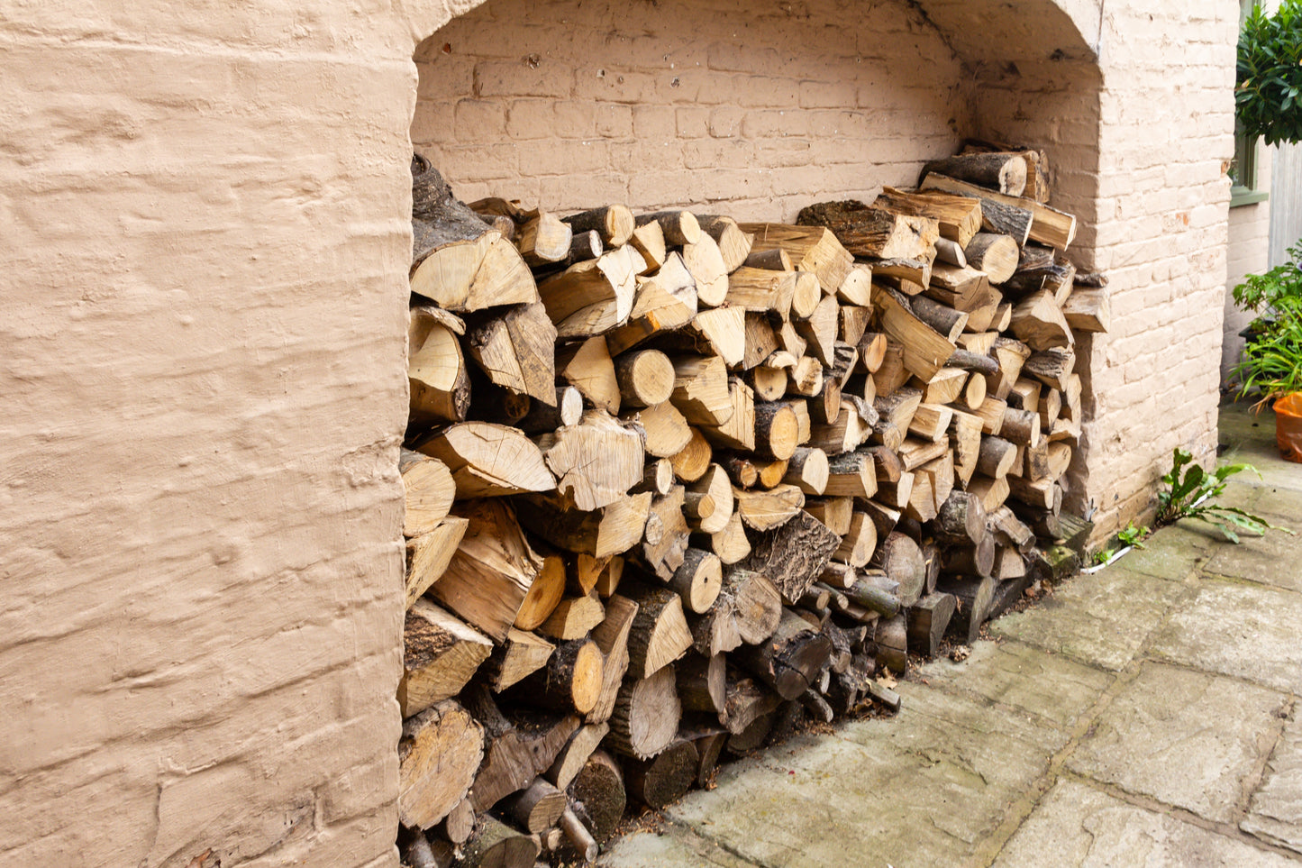 A large firewood log store by the side of the house.