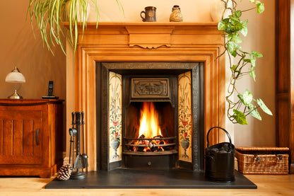 A Victorian fireplace lit with firewood logs.