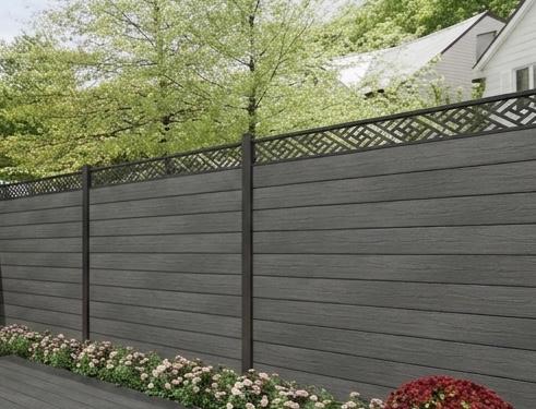 Grey fence with decorative top section in a garden setting