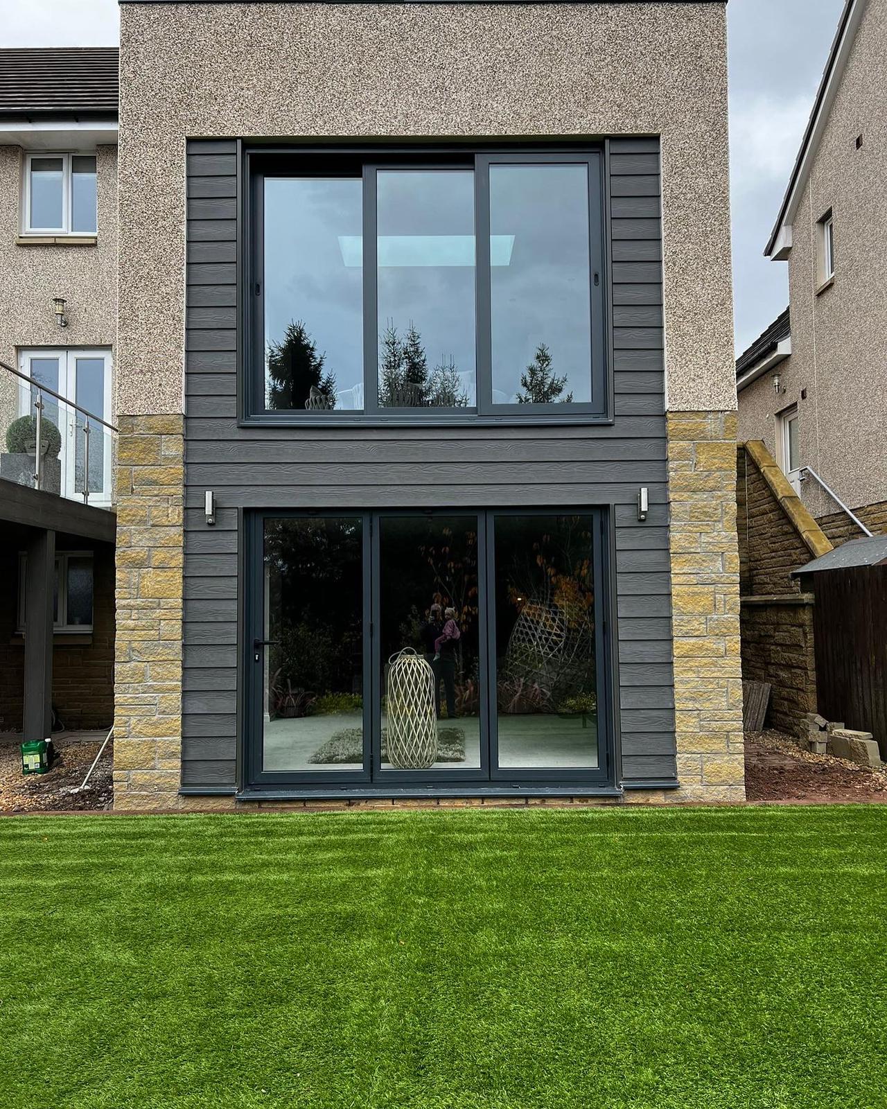 A modern home with steel grey wood grain cladding on the front elevation from The Grass Yard.