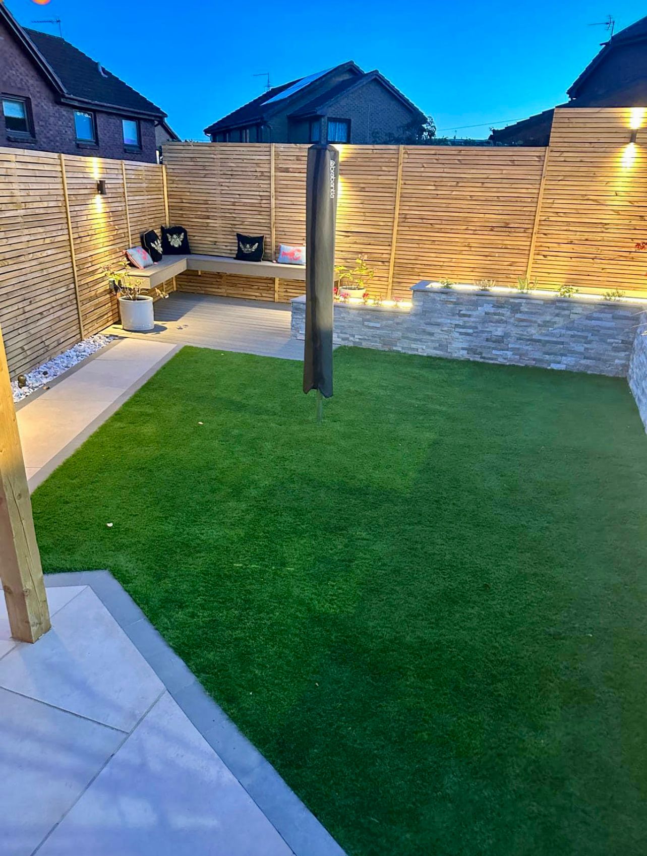 Slatted wooden fence battens in a customers back garden along with porcelain and artificial grass.