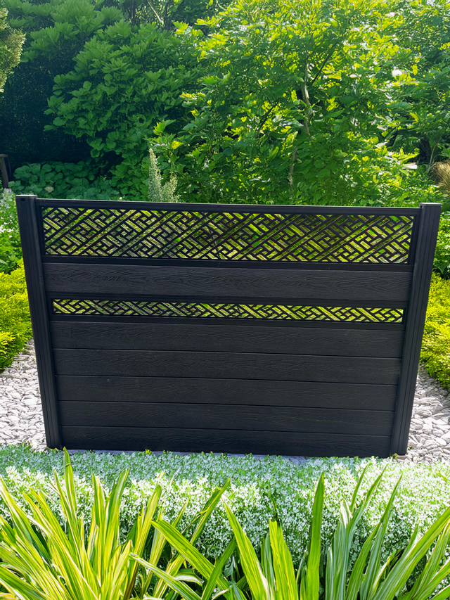 Black decorative screen with geometric pattern in a garden setting