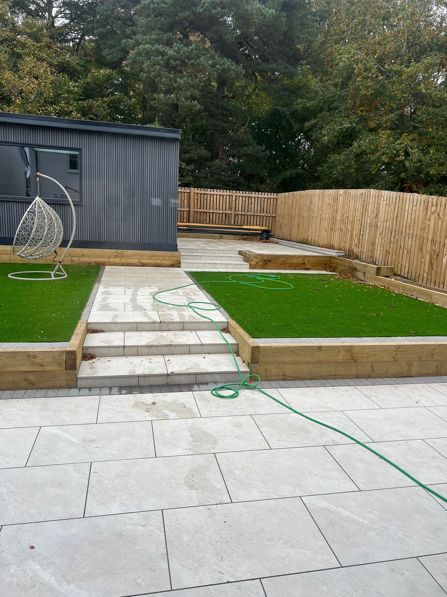 A garden landscaping project with artificial grass and garden room finished of with composite steel grey slat cladding.